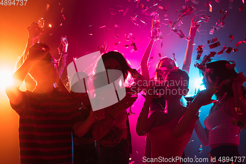 Image of A crowd of people in silhouette raises their hands on dancefloor on neon light background