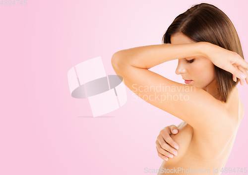 Image of young woman checking breast for signs of cancer