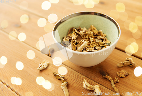 Image of dried mushrooms in bowl on wooden background