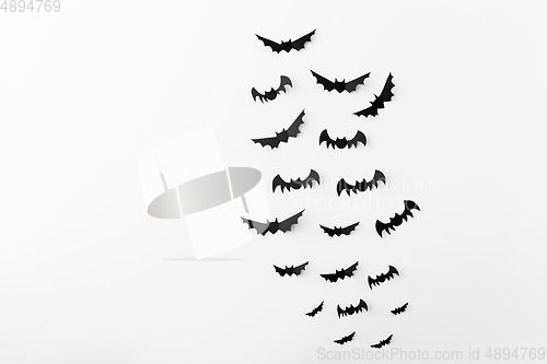 Image of flock of black paper bats over white background