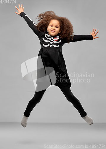 Image of girl in halloween costume of skeleton jumping