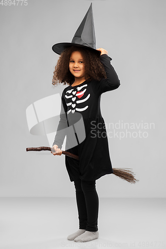 Image of girl in black witch hat with broom on halloween