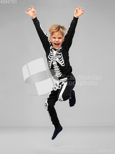 Image of happy boy in halloween costume of skeleton jumping