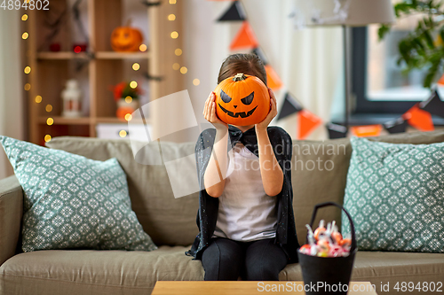 Image of girl in halloween costume with pumpkin at home
