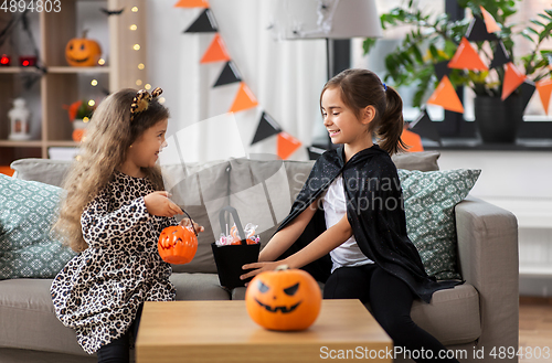 Image of girls in halloween costumes with candies at home