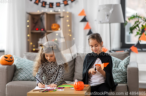 Image of girls in halloween costumes doing crafts at home