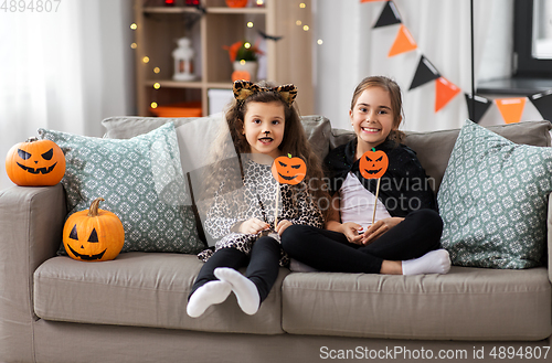 Image of girls in halloween costumes with pumpkins at home