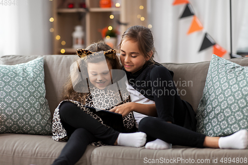 Image of girls in halloween costumes with tablet pc at home