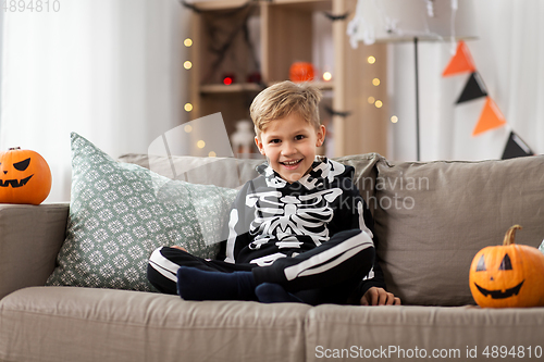 Image of happy boy in halloween costume of skeleton at home