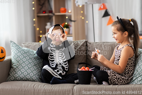 Image of kids in halloween costumes with candies at home
