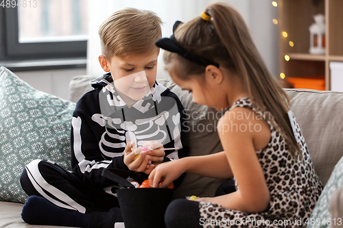 Image of kids in halloween costumes with candies at home