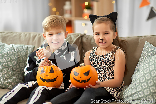 Image of kids in halloween costumes with pumpkins at home