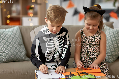 Image of kids in halloween costumes doing crafts at home