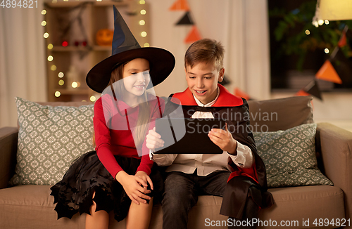 Image of kids in halloween costumes with tablet pc at home