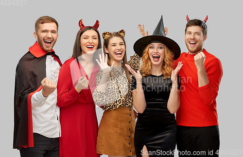 Image of happy friends in halloween costumes over grey