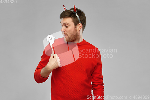 Image of happy man in halloween costume of devil over grey