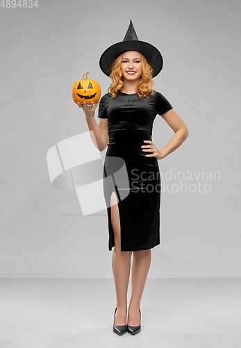 Image of woman in halloween costume of witch with pumpkin