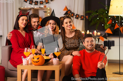 Image of happy friends in halloween costumes taking selfie