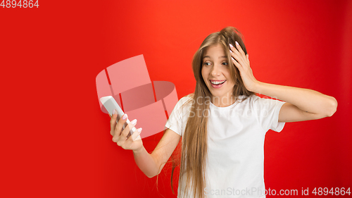 Image of Portrait of young caucasian woman with bright emotions on bright red studio background