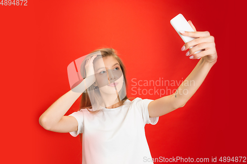 Image of Portrait of young caucasian woman with bright emotions on bright red studio background