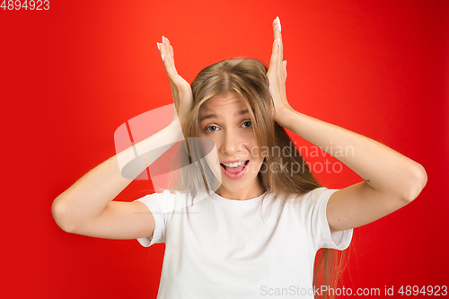 Image of Portrait of young caucasian woman with bright emotions on bright red studio background