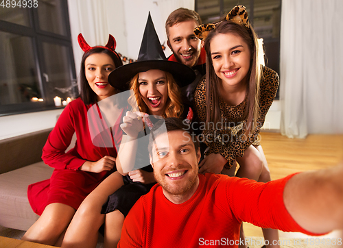 Image of happy friends in halloween costumes taking selfie