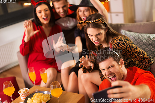 Image of happy friends in halloween costumes taking selfie