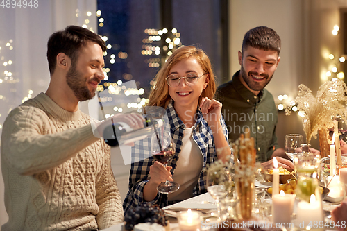 Image of happy friends with red wine at christmas party