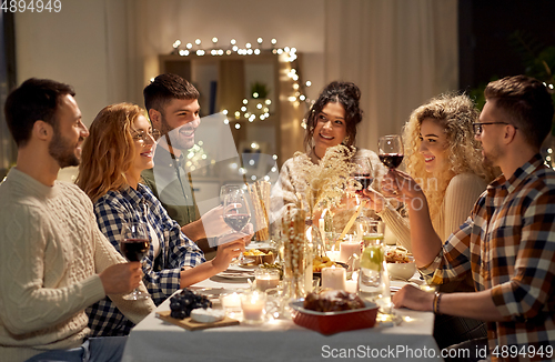 Image of happy friends drinking red wine at christmas party