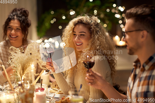 Image of happy friends drinking red wine at christmas party