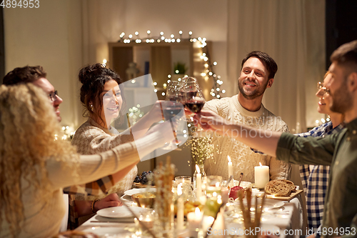 Image of happy friends drinking red wine at christmas party