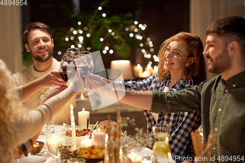 Image of happy friends drinking red wine at christmas party