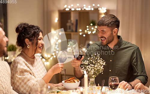 Image of happy friends drinking red wine at christmas party