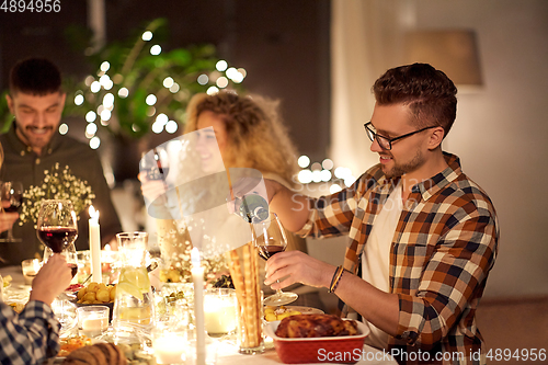 Image of man pouring red wine to glass at dinner party