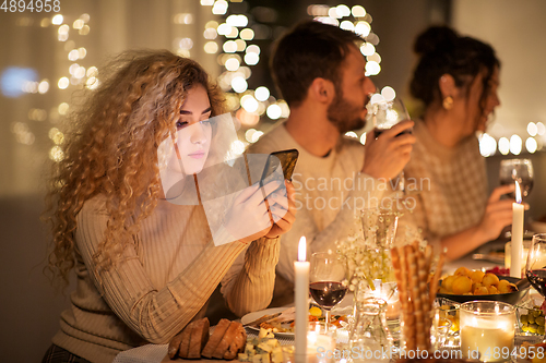 Image of woman with smartphone at dinner party with friends