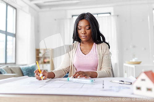 Image of female architect with house model and blueprint