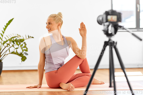 Image of woman with camera streaming for yoga blog at home