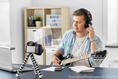 Image of man or blogger with camera playing guitar at home