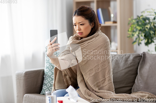 Image of sick asian woman with smartphone at home