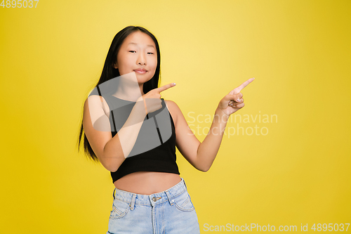 Image of Portrait of young asian girl isolated on yellow studio background