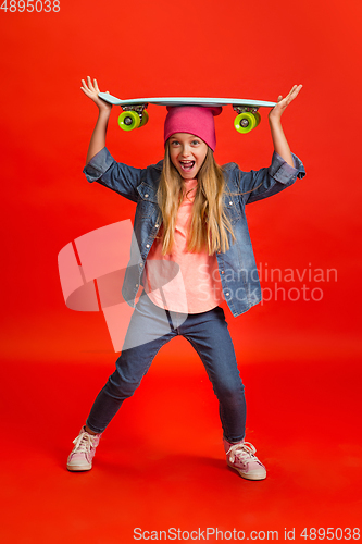 Image of Caucasian little girl portrait isolated on red studio background. Cute stylish model