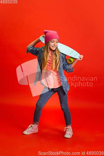 Image of Caucasian little girl portrait isolated on red studio background. Cute stylish model
