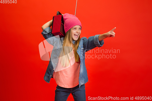 Image of Caucasian little girl portrait isolated on red studio background. Cute stylish model