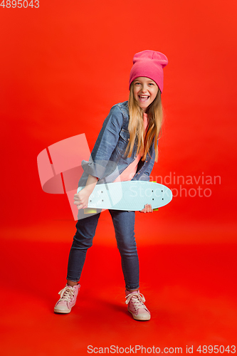 Image of Caucasian little girl portrait isolated on red studio background. Cute stylish model