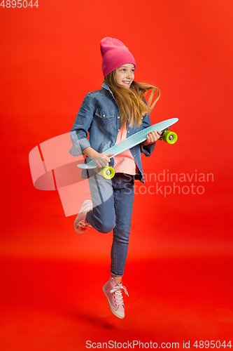 Image of Caucasian little girl portrait isolated on red studio background. Cute stylish model