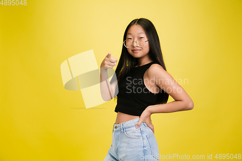 Image of Portrait of young asian girl isolated on yellow studio background