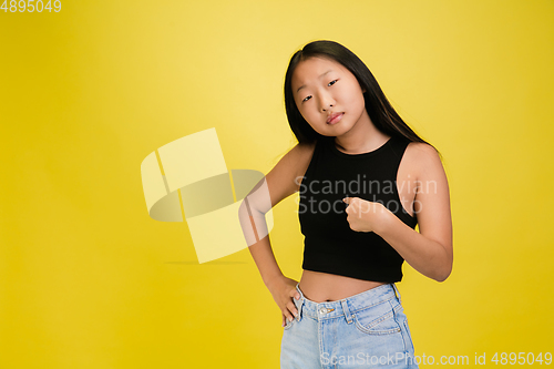 Image of Portrait of young asian girl isolated on yellow studio background