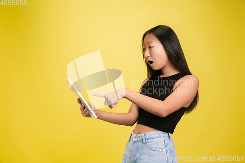 Image of Portrait of young asian girl isolated on yellow studio background