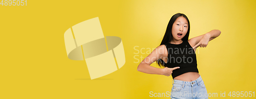 Image of Portrait of young asian girl isolated on yellow studio background