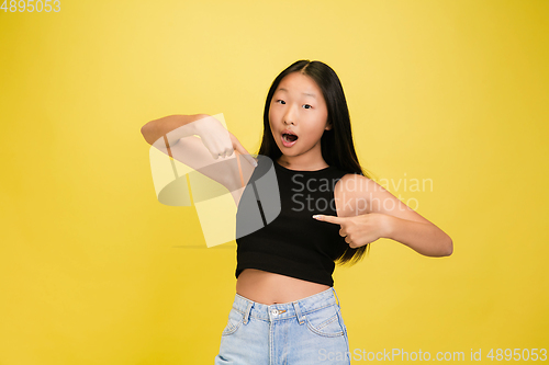 Image of Portrait of young asian girl isolated on yellow studio background